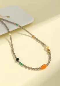 Detalle de collar de cuentas de cuarzo ahumado con colgante de jade de seda dorada