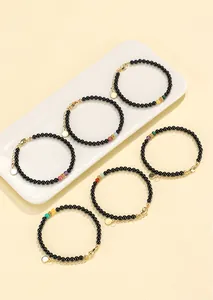 Detailed close-up of multiple black agate beaded bracelets featuring various colorful gemstones.