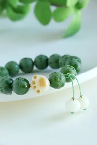 Detailed macro shot of green Bodhi beads with carved mantra and ceramic cat paw charm