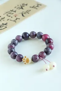 Detailed view of purple mantra beads with charred cat paw charm on Bodhi bracelet