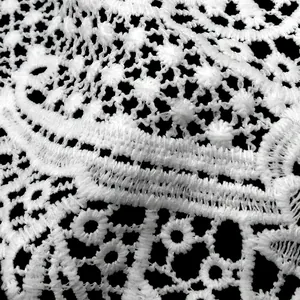 Macro view showing the intricate details of white lace embroidery with hollow-out floral patterns