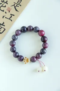 High-quality detail of purple bodhi bead bracelet with engraved mantra and cat paw charm