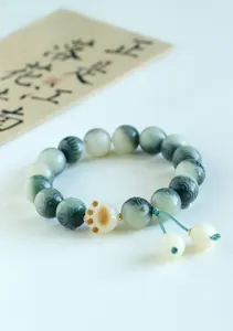 Detail showing the ceramic cat paw charm and green textured beads on this prayer bracelet.