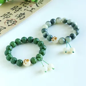 Detail view of green mantra bodhi bead bracelets featuring cute white cat paw charms.