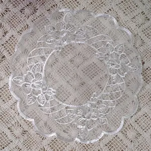 Detailed close-up of white organza embroidered lace placemat with intricate floral patterns