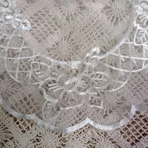 Detailed macro view of delicate floral embroidery on white organza lace table mat