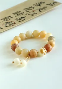 Macro detail of natural Bodhi bead bracelet featuring a cute cat paw charm and swirly patterns