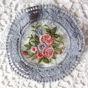 Detalle en primer plano de un posavasos de encaje vintage con bordados florales