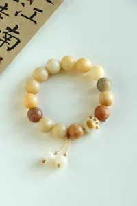 Macro view of carbonized Bodhi bead bracelet featuring a cute white cat paw charm