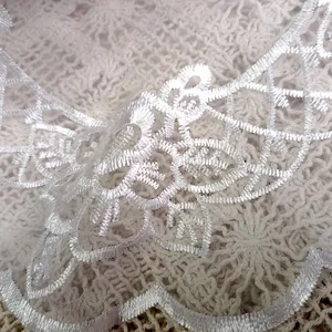 Close-up detail of white embroidered lace coaster with delicate organza floral pattern.