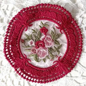 Detalle de un posavasos bordado en encaje rojo de estilo europeo con flores