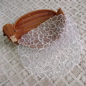 Detailed texture of white organza embroidered lace table mat with floral patterns.