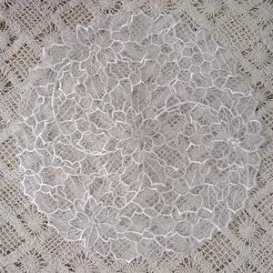 Detail shot showing intricate white organza floral embroidery on a lace coaster