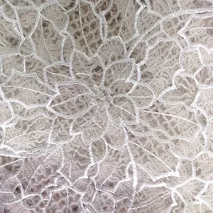 Close-up detail of delicate white organza embroidered lace placemat with floral pattern