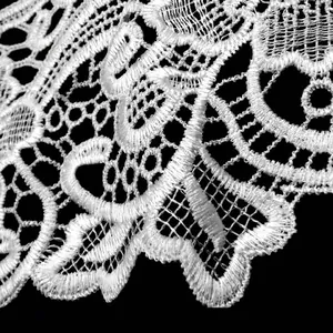 Macro view of white water-soluble lace collar embroidery showing delicate floral patterns