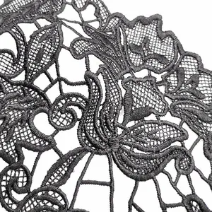 Detailed macro shot of black water-soluble lace embroidery with hollow floral patterns.