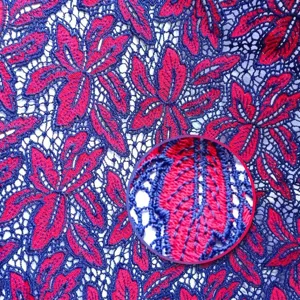 Detailed macro view of red and blue floral water-soluble embroidered lace fabric