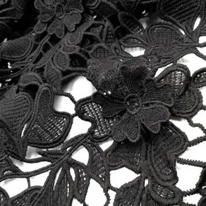 Detailed macro view of black water-soluble milk silk lace fabric with 3D floral embroidery