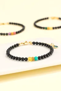 Detailed close-up of a black onyx bead bracelet featuring vibrant turquoise and amber accents