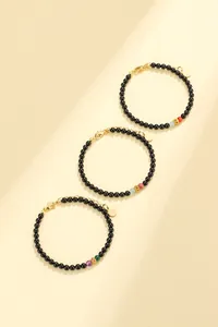 Set of three black onyx beaded bracelets with colorful gemstone accents and gold charms.