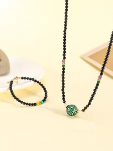 Detail view of black onyx beaded necklace and bracelet set with green lacquer bead