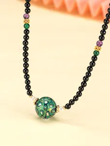 Detail of a beaded necklace featuring black agate, amethyst, and green lacquer beads.