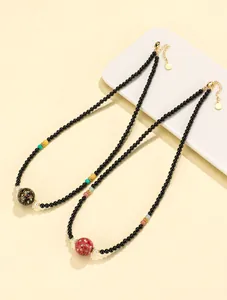 Detail showing handcrafted lacquer beads on black agate necklaces in a new Chinese style