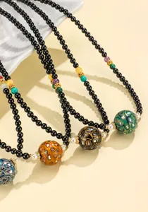 Detailed macro view of black agate jewelry necklaces featuring vibrant patterned lacquer beads.