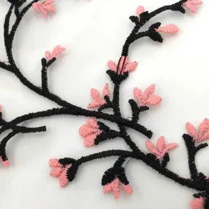 Macro view showing detailed pink cherry blossom and black branch embroidery on fine mesh fabric