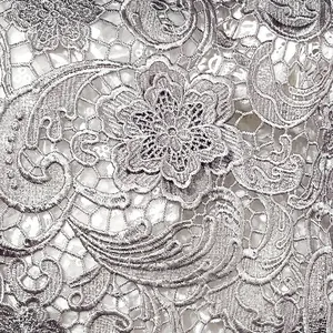 Vue macro détaillée du tissu en dentelle soluble dans l'eau brodé de motifs paisley argentés