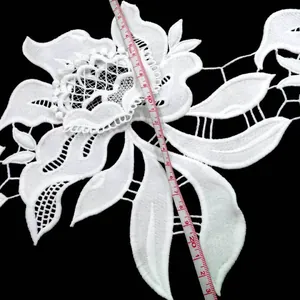 Detailed close-up of white milk silk floral embroidery lace with scale measurement