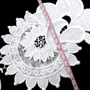 Detailed close-up of white water-soluble milk silk 3D lace trim with measuring tape
