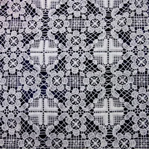 Close-up of white water-soluble lace fabric with intricate hollow floral embroidery.