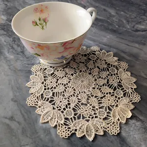 Detailed view of an elegant white lace embroidered round coaster doily on marble surface