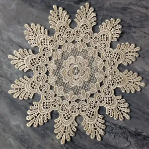 Close-up of a vintage beige lace embroidered coaster with intricate floral hollow-out design.