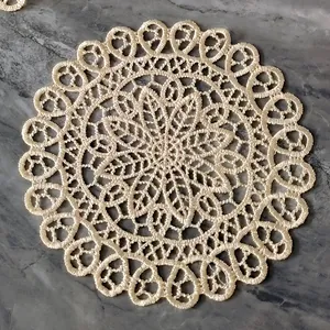 Close-up detail of an intricate ivory lace embroidered round coaster on a grey marble background