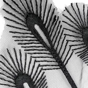 Detailed macro view of black embroidered peacock feather lace motifs on fine mesh fabric.