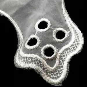 Macro view of white water-soluble lace fabric with delicate floral embroidery and eyelets