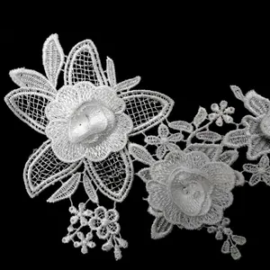 Close-up of white 3D floral lace embroidery with delicate hollow-out pattern on black