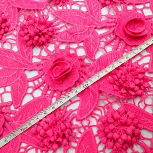 Close-up view of rose red 3D floral lace fabric with a measuring tape for size scale