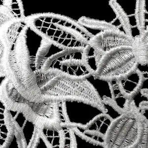 Detailed close-up of white water-soluble lace embroidery with intricate hollow-out patterns.