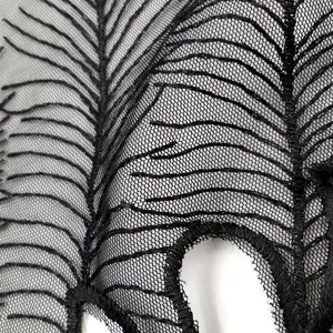 Gros plan sur une application de col en dentelle brodée noire avec motifs de plumes fins