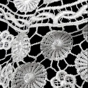 Macro detail of white water-soluble lace embroidery with intricate floral hollow patterns.