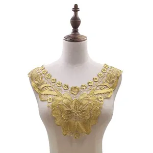 Detail of a gold water-soluble lace collar with floral embroidery on a mannequin.