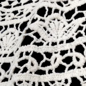 Macro view of intricate white lace crochet pattern and hollowed-out fabric detail