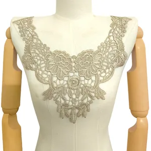 Détail montrant la broderie complexe en dentelle dorée sur un col appliqué floral.