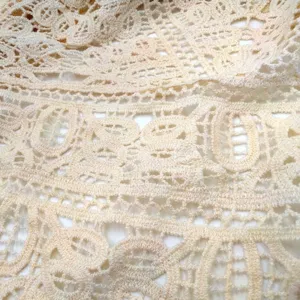 Close-up macro detail of cream cotton water-soluble lace with hollow floral embroidery