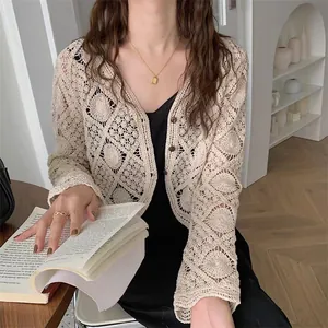 Close-up of beige crocheted lace cardigan with intricate hollow-out geometric patterns