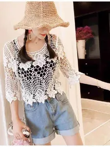 Detail view of a white hollow-out lace crochet top featuring intricate floral patterns