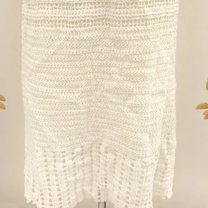 Vue détaillée du motif complexe au crochet blanc sur la robe de plage